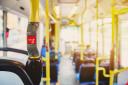 Red button STOP on the bus. Bus with yellow handrails and blue seats. Photo with the sun effect, glare on the lens from the light. Spacious interior of the bus, bright button with focus (Red button STOP on the bus. Bus with yellow handrails and blue s