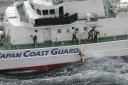 Japanese coastguard members pick up a floating object as they conduct search and rescue operation in the waters off Yakushima Island, Kagoshima prefecture, southern Japan on Thursday (Kyodo News via AP)