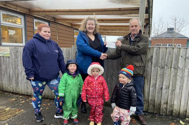 Chester Lions Club President Graham O'Reilly presenting a cheque to Kate Linford, Preschool committee chair, watched by school manager Lyndsey McCallion and three of the schoolchildren.