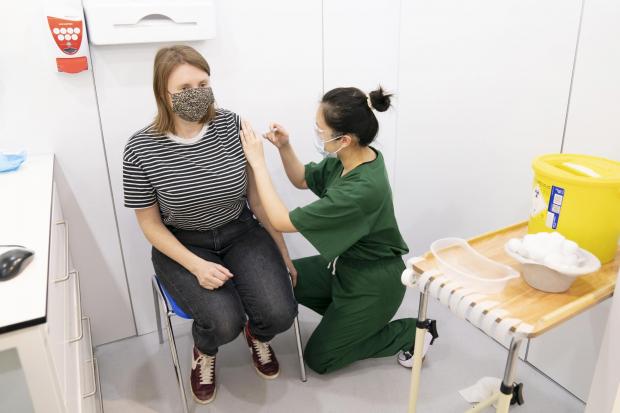 Wendy Geng (right) administers a booster coronavirus vaccine to Philippa Nall (left) at a Covid vaccination centre at Elland Road in Leeds (Danny Lawson/PA)